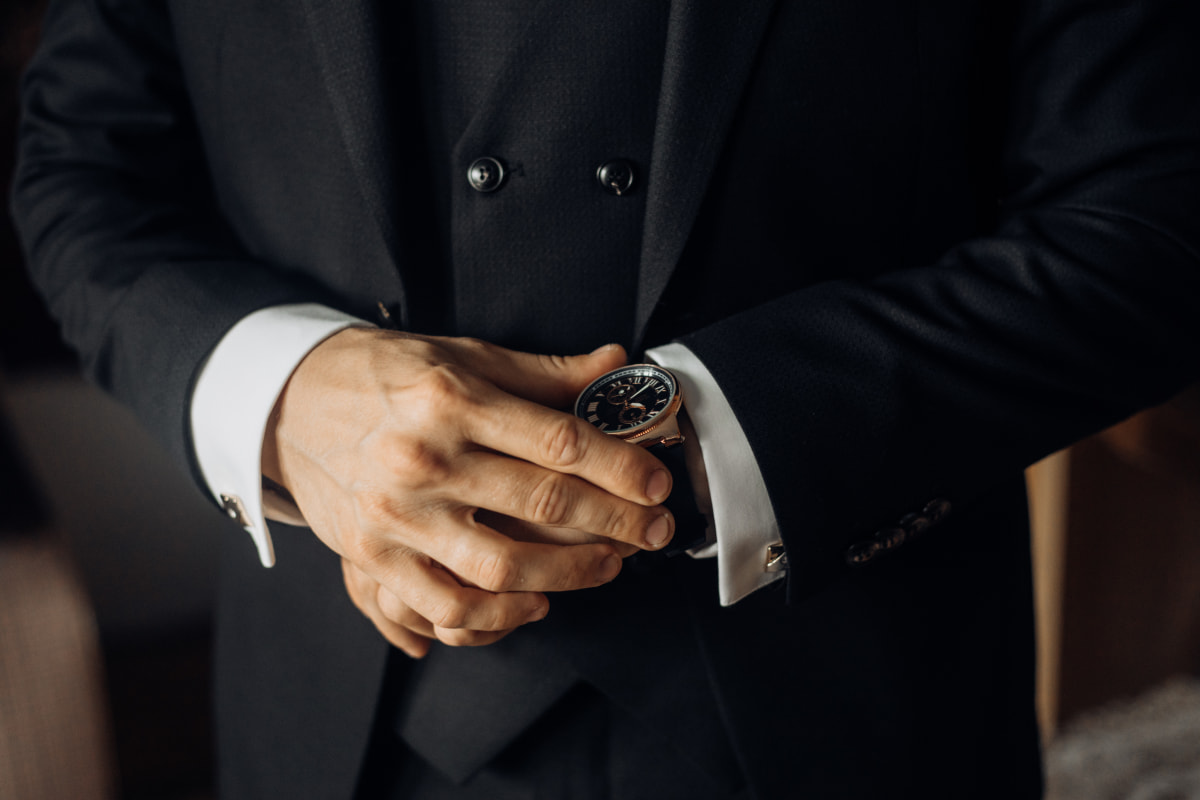 Homme en costume élégant ajustant sa montre bracelet au poignet