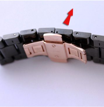 Mécanisme de fermeture ouvert d'un bracelet de montre noir et or rose avec flèche