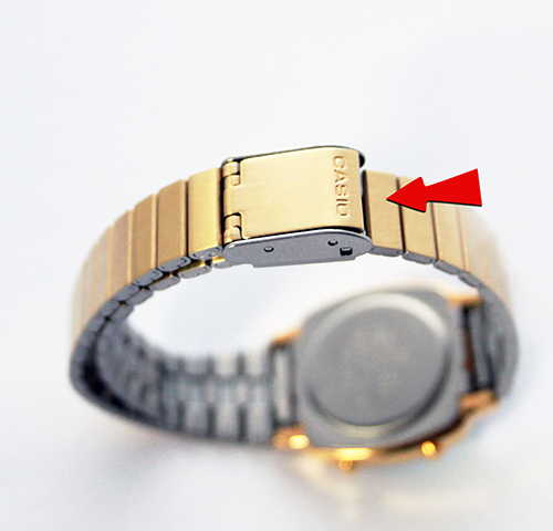 Bracelet de montre doré métallique avec fermoir Casio et flèche rouge pointant un maillon