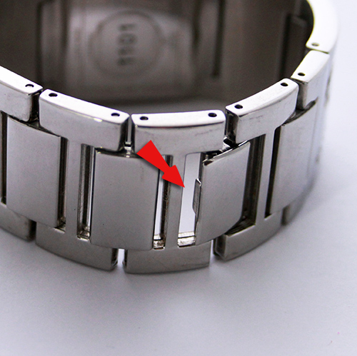 Gros plan sur le fermoir métallique d'un bracelet de montre avec flèche rouge