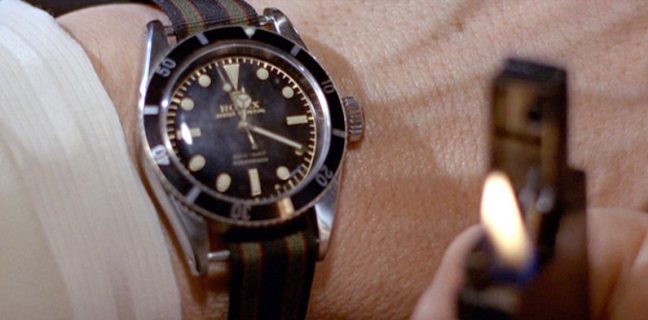 Montre Rolex sur poignet avec bracelet de montre NATO rayé et briquet allumé