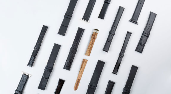 Multiples bracelets de montre en cuir noir et liège, différentes textures, sur fond clair