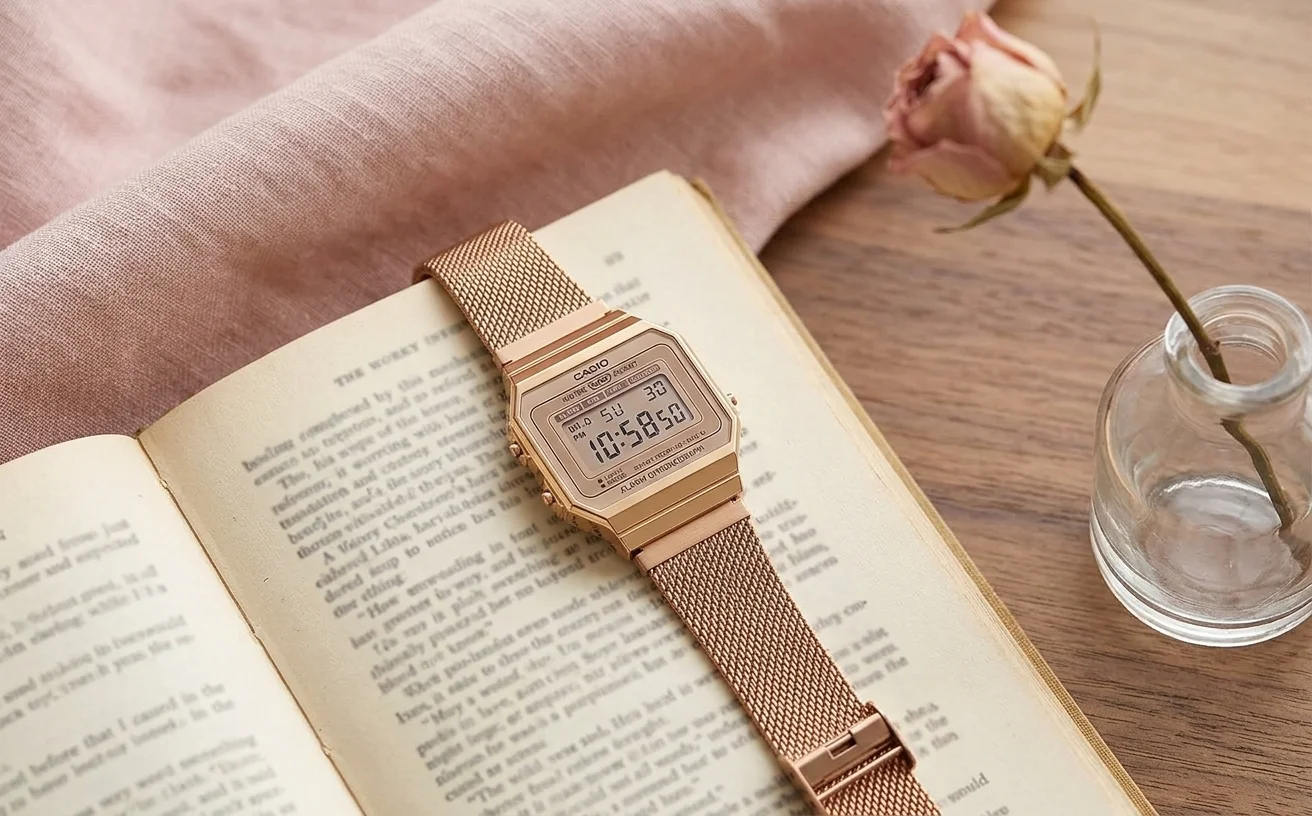 Casio A700 bracelet maille milanaise rose gold posée sur un livre à la couverture pastel